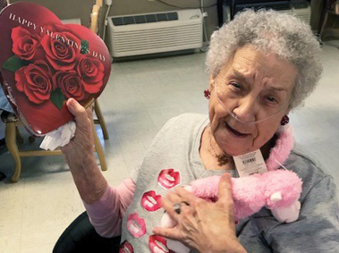 senior resident holding box of candy and teddy bear