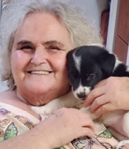 Resident Judy T holding a black and white puppy close to her face