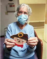 Irvine Nursing and Rehab resident showing off her scarecrow craft