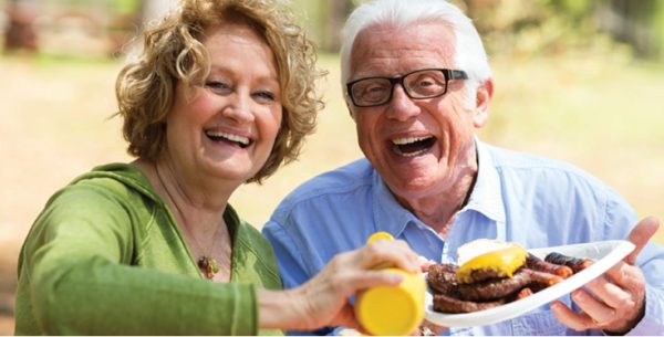 senior woman and senior man sitting at picnic table eating