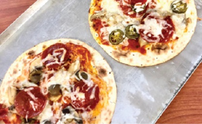 two homemade pizzas with toppings on table