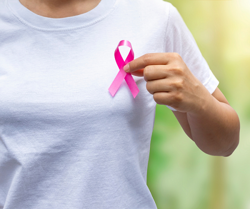 young woman pinning a pink ribbon to her tshirt for Breast Cancer Awareness