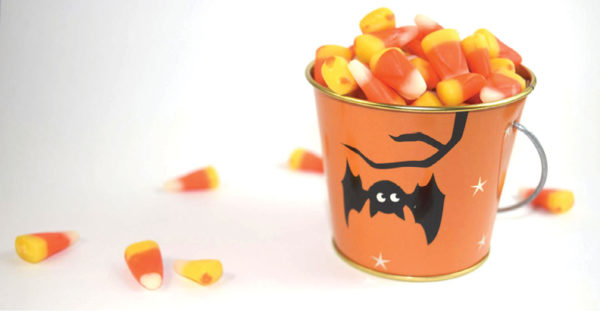 candy corn candies in a small orange tin bucket on white background