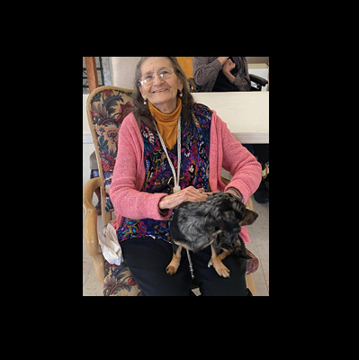 older woman sitting in a chair with cute black puppy sitting on her lap